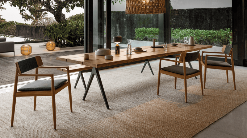 Vue de côté de la chaise Archi contre une table, elle combine teck et corde outdoor pour une expérience de confort unique en extérieur. Découvrez-la chez Homa, à Coustellet.